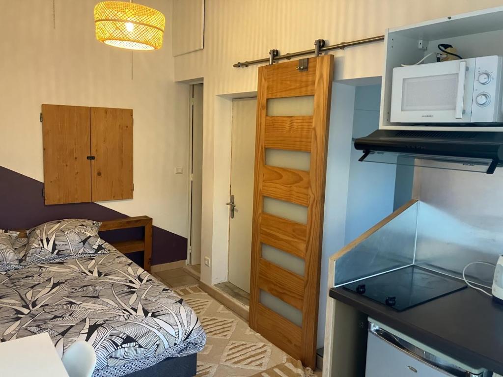 um pequeno quarto com uma cama e um micro-ondas em Le Nid Castries - Charmant logement complet et équipé Centre Castries proche Montpellier em Castries