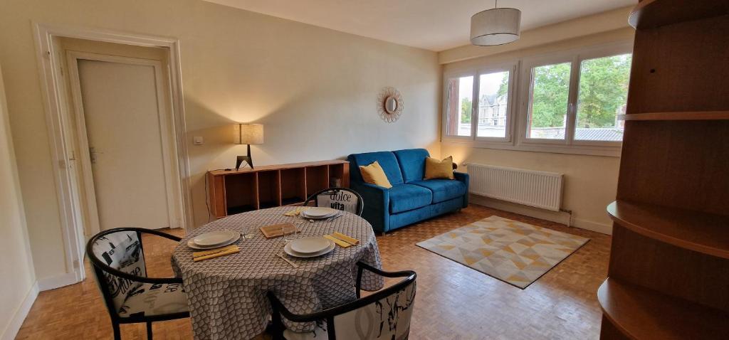un soggiorno con tavolo e divano blu di Le Sleipnir - Appartement cantilien calme (proche gare SNCF) a Chantilly