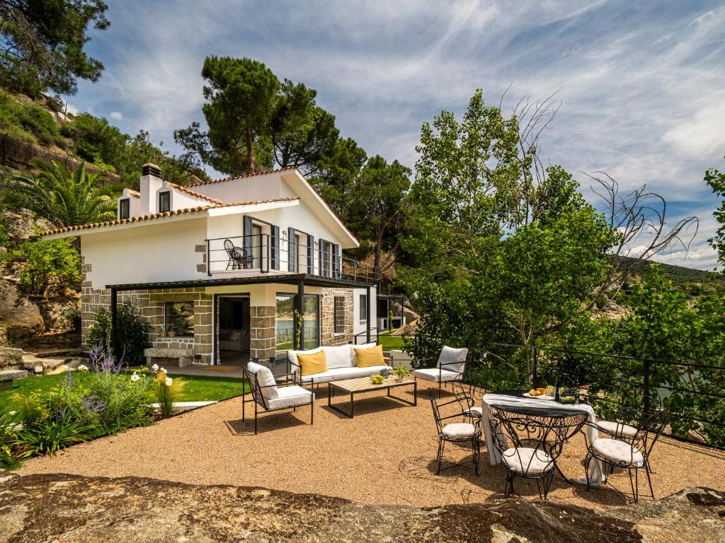 a house with a patio with chairs and a table at Casa junto al Pantano de Burguillo in El Tiemblo