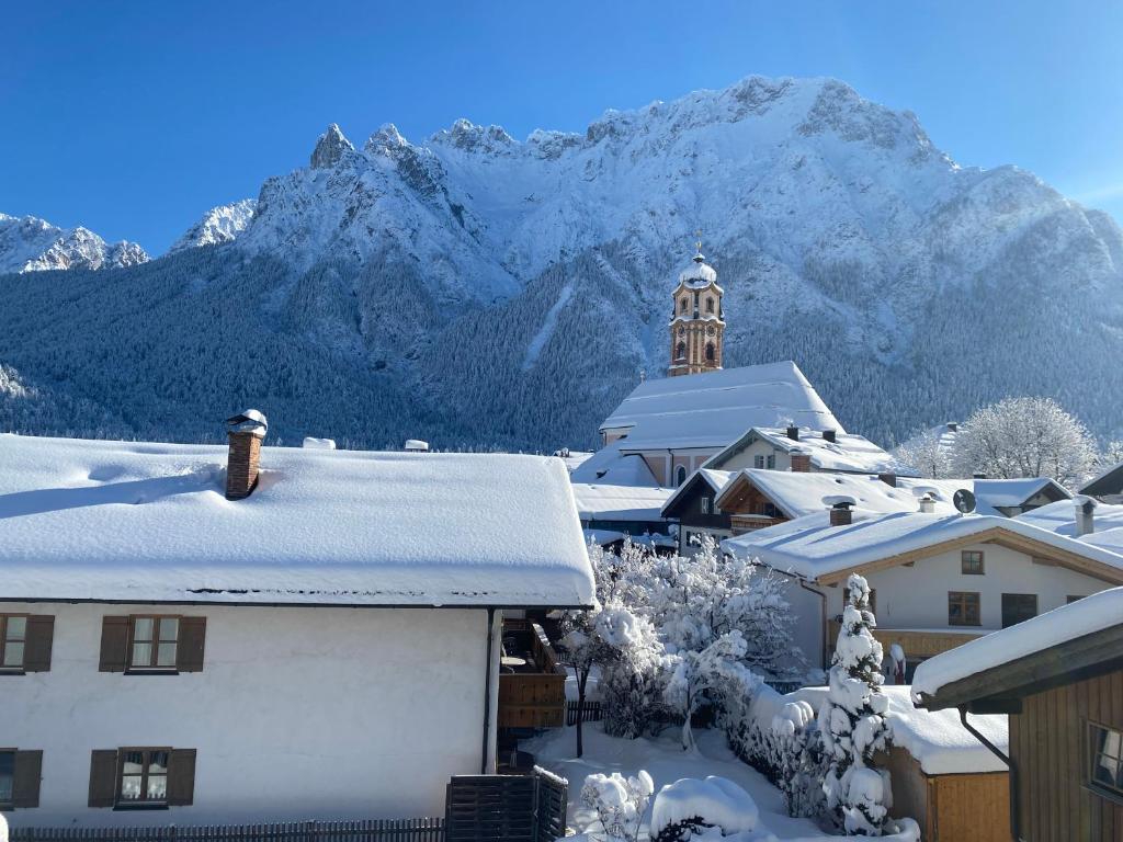 un pueblo cubierto de nieve con una montaña en el fondo en Haus Heimatfrieden Mittenwald, en Mittenwald