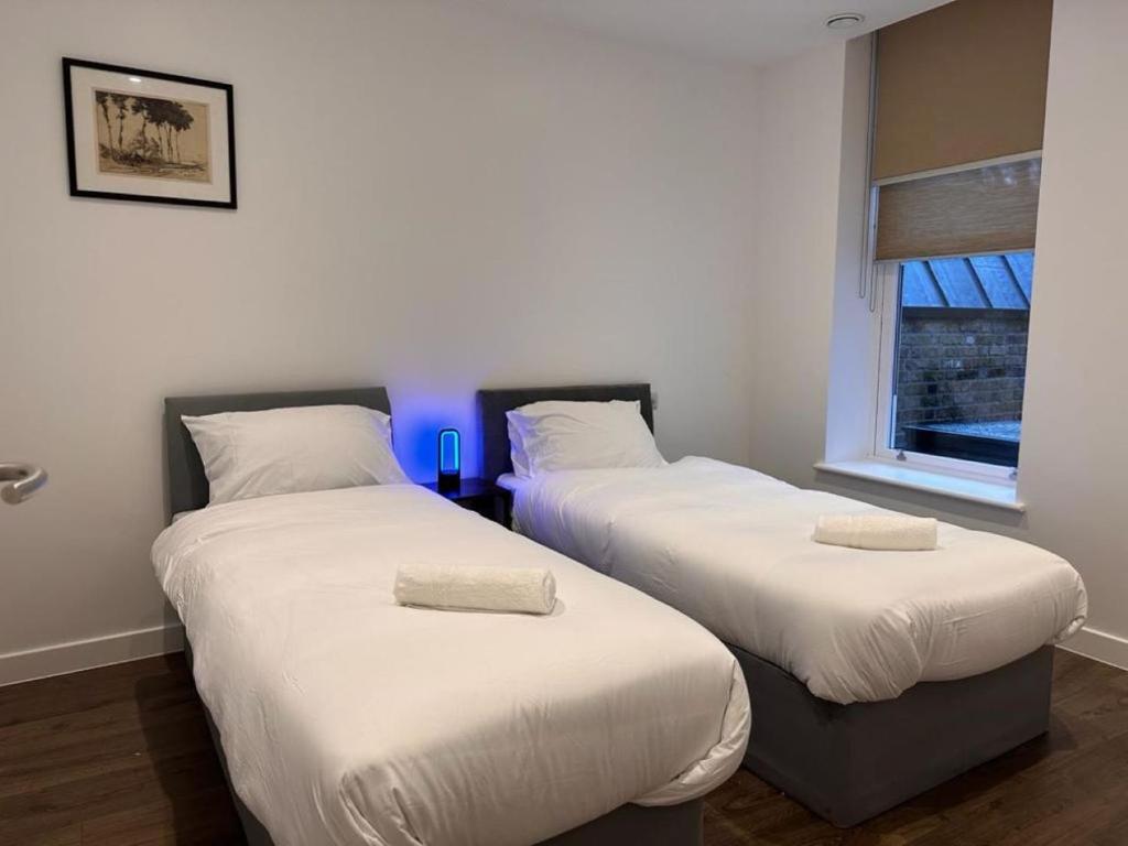 two beds in a room with a blue light at Farringdon Apartments in London