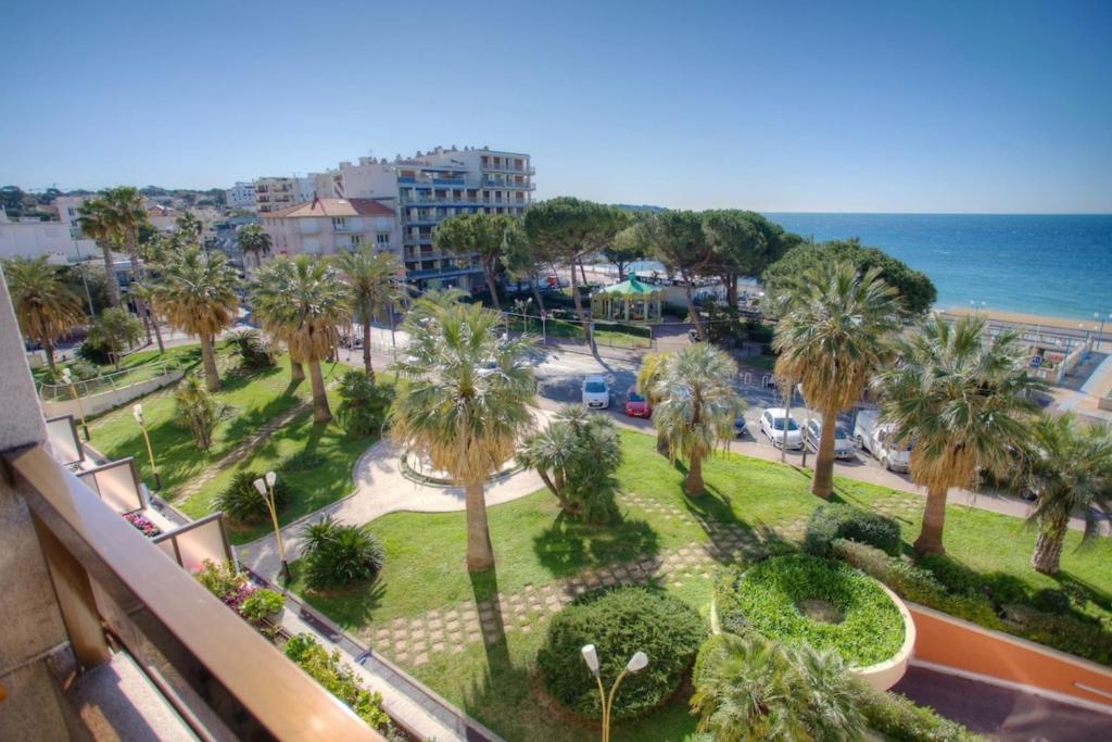 uma vista para um parque com palmeiras e o oceano em 06AY - Studio with seafront terrace em Antibes