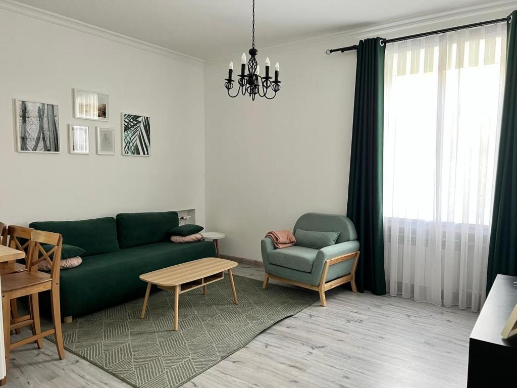 sala de estar con sofá verde y silla en DOWNTOWN APPARTMENTS, en Karagandá