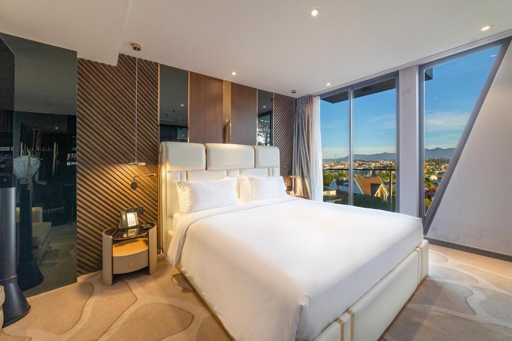 a bedroom with a large white bed and large windows at New Century Dalat Hotel in Da Lat