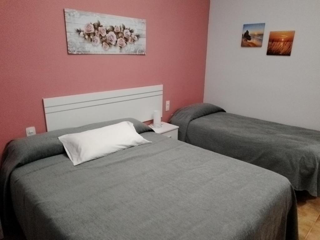 two beds in a room with red walls at Las/Rosas in Orgaz
