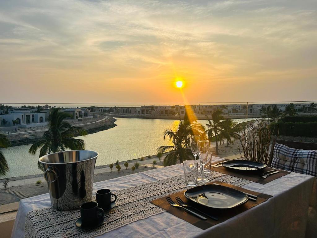 a table with a view of a river and the sunset at 1-Bedroom in Forest Island & Oceanside View in Salalah