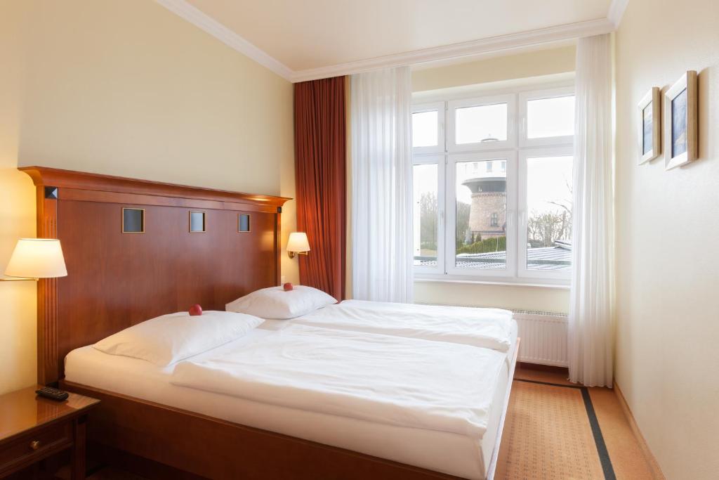 a bedroom with a bed and a large window at Vju Hotel Rügen in Göhren
