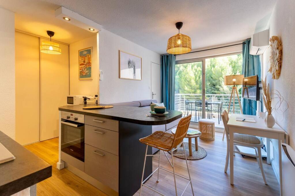 cocina con encimera, mesa y sillas en Appartement rénové, calme et proche des plages., en Sète