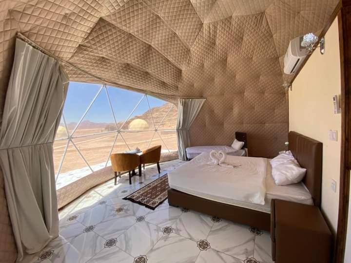 a bedroom with a bed and a view of the desert at Miral Night Camp in Wadi Rum