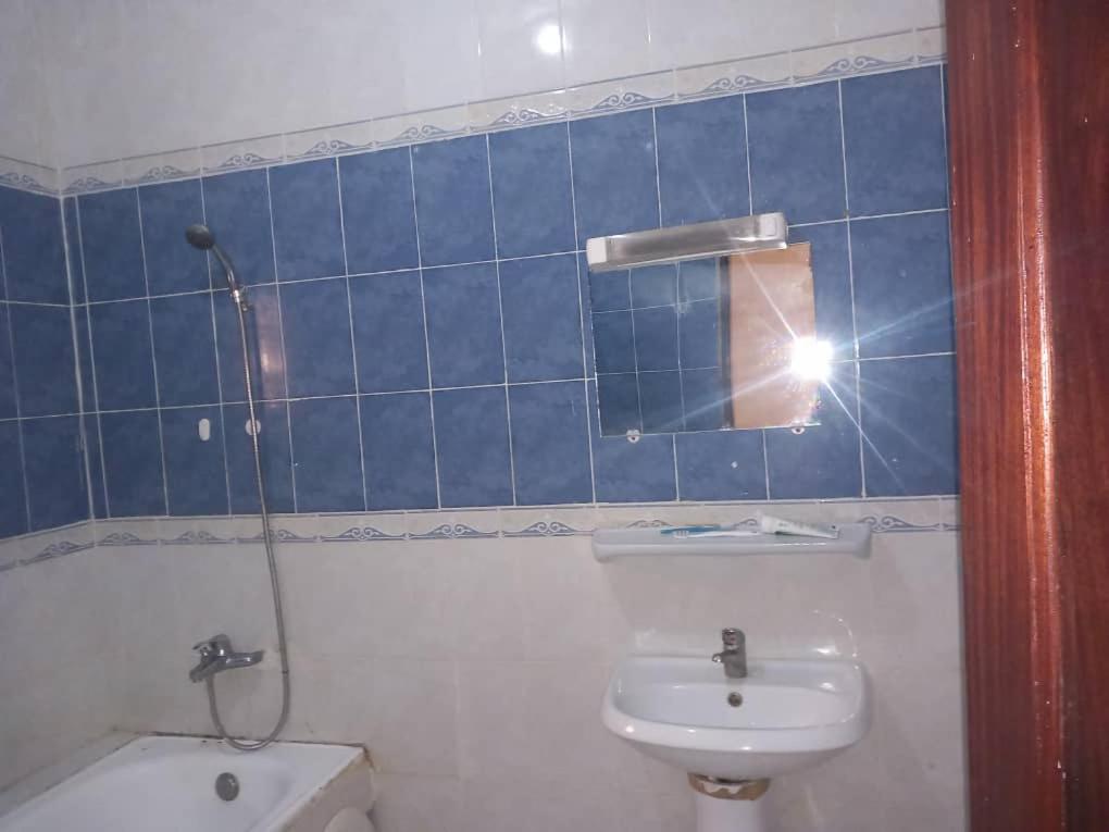 a bathroom with a sink and a toilet and a mirror at Chambre Chez Jean in Nouakchott