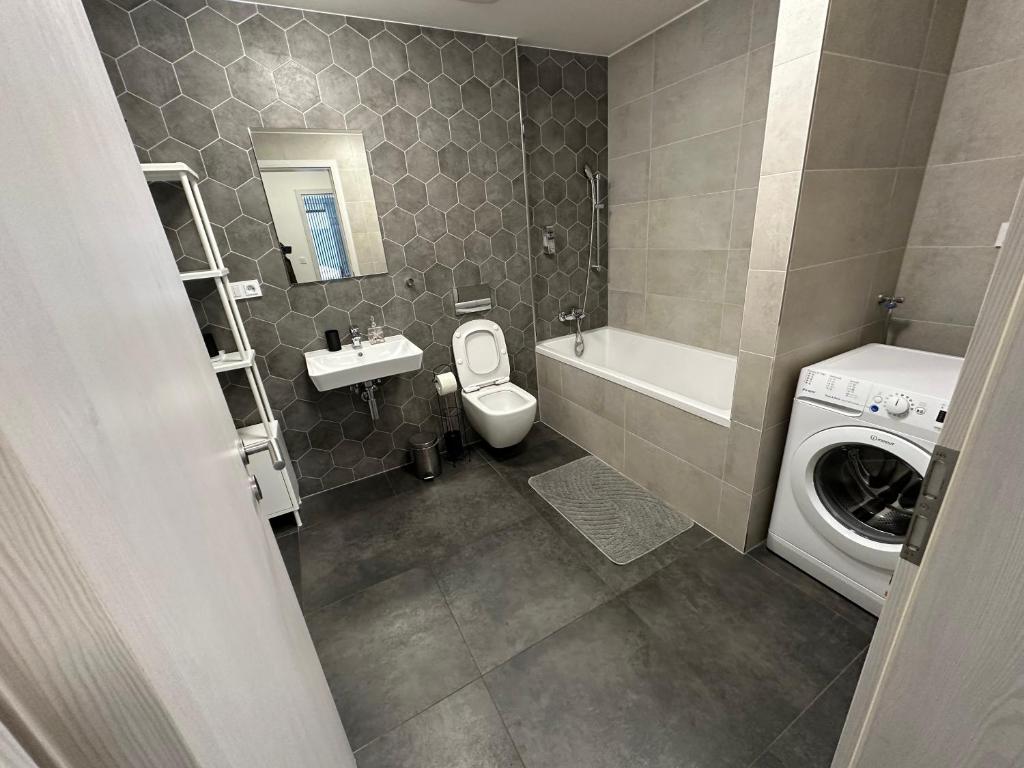 a bathroom with a toilet sink and a washing machine at O2 Arena - Alex Apartment Praha in Prague