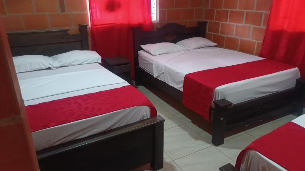 two beds in a room with red curtains at Hotel campestre la isla in Neiva