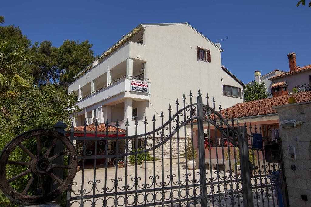 een wit huis met een zwart hek en een gebouw bij Apartments Villa Ban in Rovinj