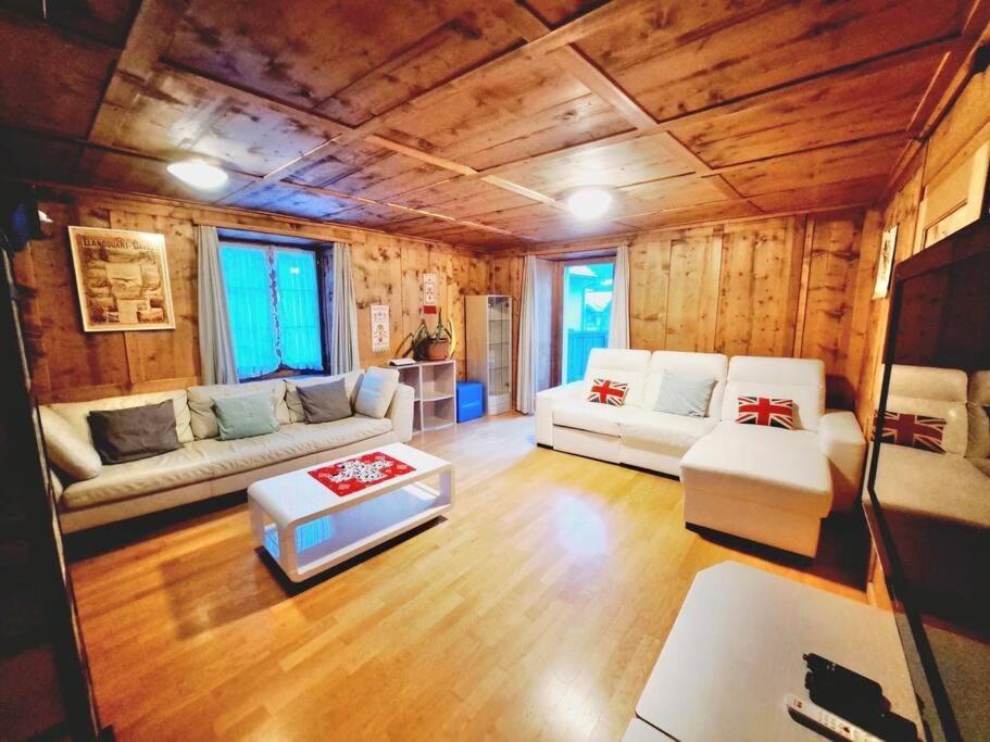 una sala de estar con muebles blancos y paredes de madera. en Höflihaus, Maienfeld, en Maienfeld
