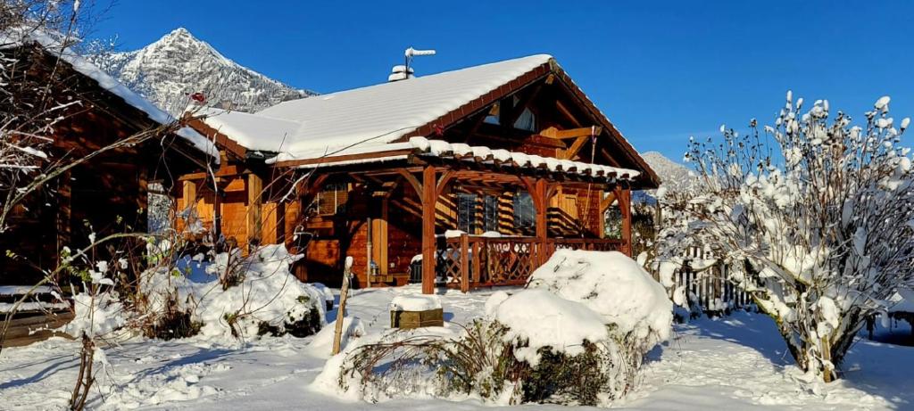 una cabaña de madera cubierta de nieve con una montaña en Chalet au calme en Haute Savoie., en Châtillon-sur-Cluses