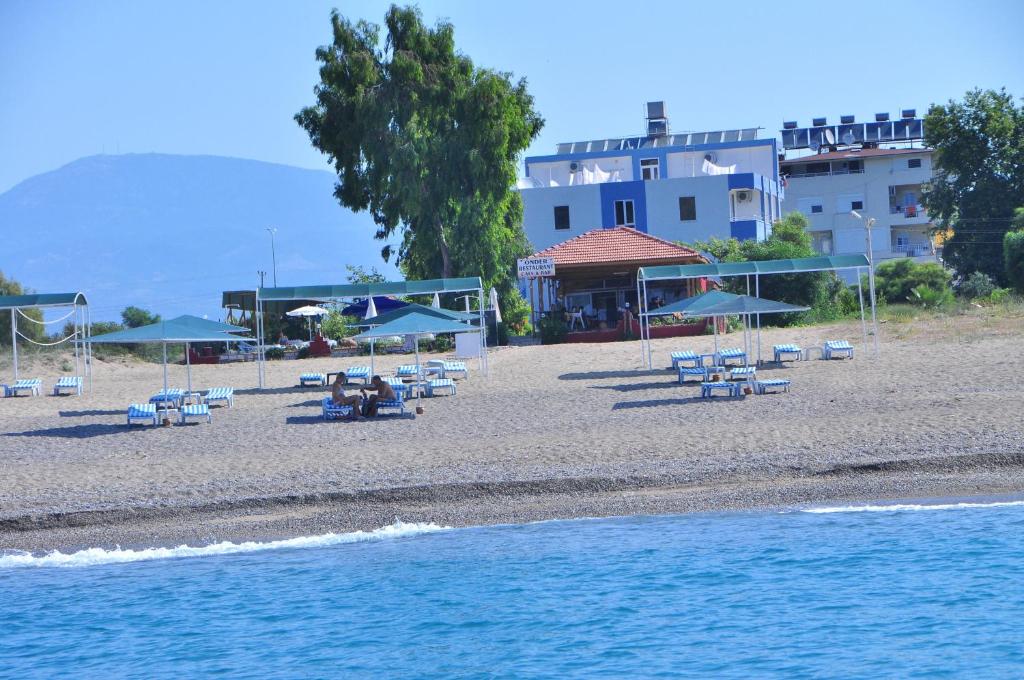 ein Strand mit Stühlen und Sonnenschirmen sowie ein Gebäude in der Unterkunft Önder Yıldız Hotel in Kızılot