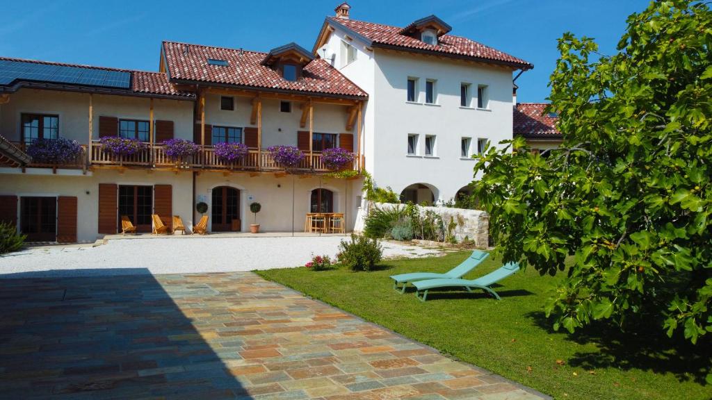 a large white house with a bench in the yard at Corte Varola B&B Zia Marisa in Belluno