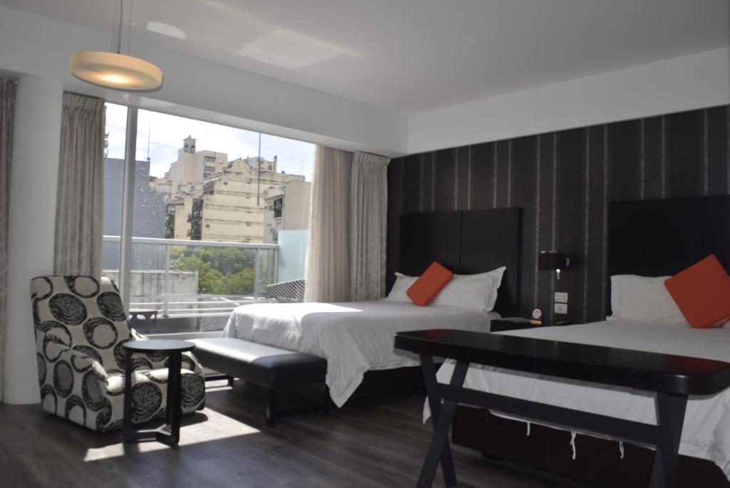 una camera d'albergo con due letti, una scrivania e una finestra di Hotel BA Abasto a Buenos Aires