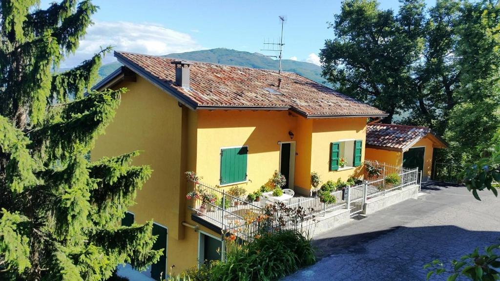 a yellow house with green shutters and a yard at Pietra di Bismantova Short Lets in Castelnovo neʼ Monti