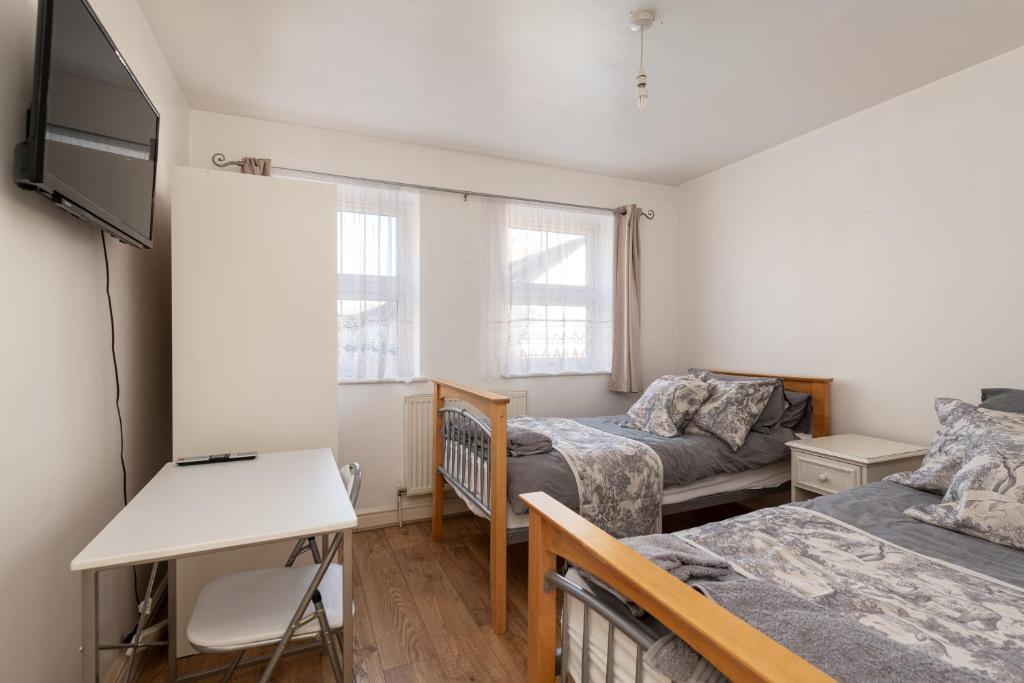 a small bedroom with two beds and a desk at Cosy Retreat - SmartTV and Wi-Fi in Gillingham