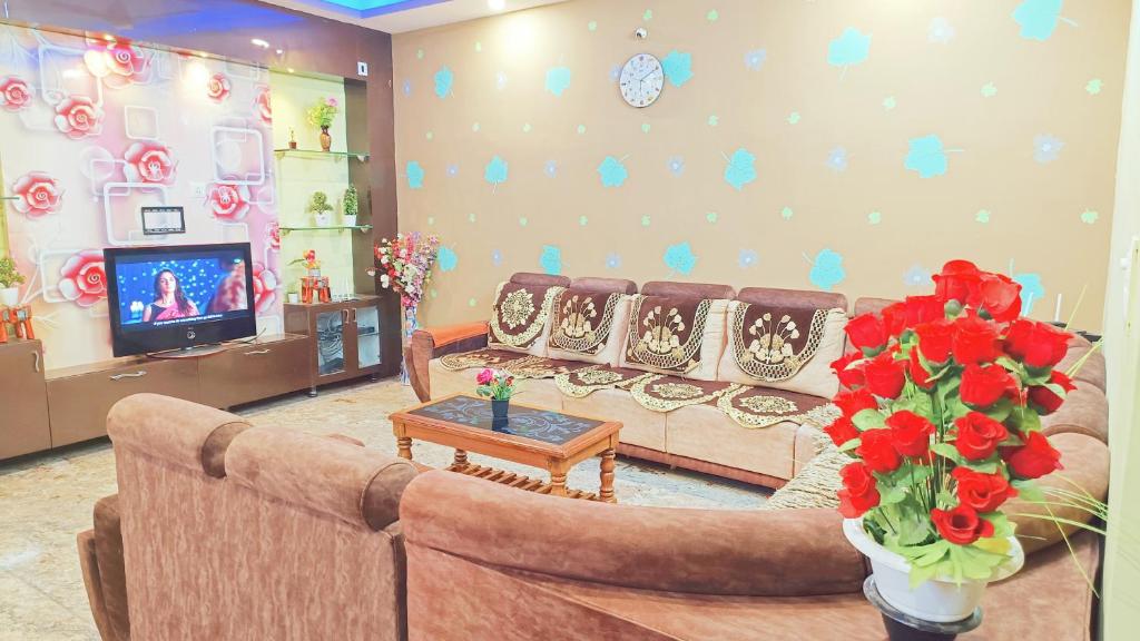 ein Wohnzimmer mit einem Sofa und einem TV in der Unterkunft Sahara premium family homestay in Mysore