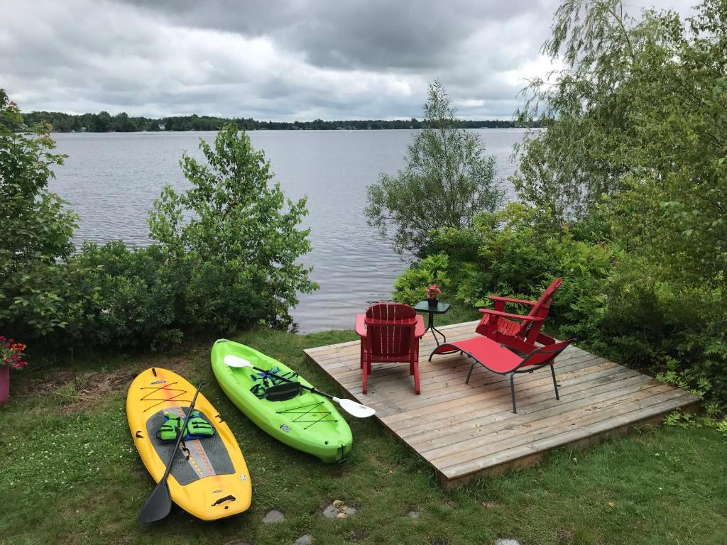 a wooden deck with a table and chairs and two kayaks at Le gîte du Lac à la Tortue in Herouxville