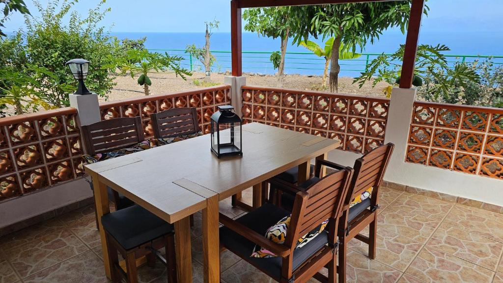 a wooden table and chairs on a balcony with the beach at Los Cerrajones: spectacular views from the cliff in Agulo