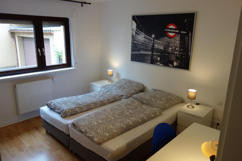 a bedroom with two beds and a table and two windows at Geräumige Ferienwohnung in ruhiger Lage in Rheinstetten