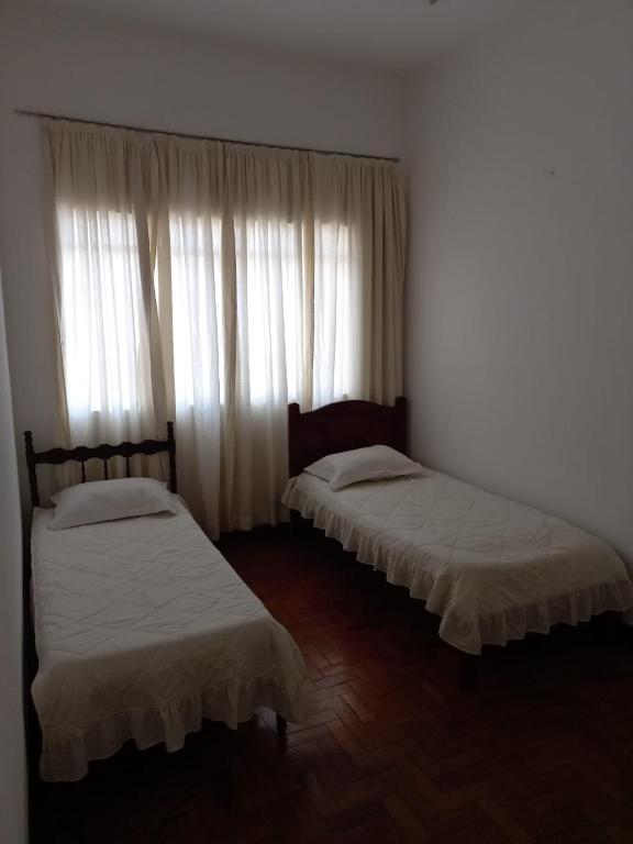 Duas camas num quarto com uma janela com cortinas em Apartamento MOBILIADO 2 QUARTOS em Volta Redonda