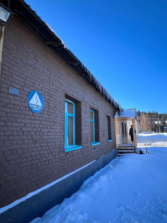 a person standing outside of a brick building in the snow at Beymaral Lodge Jyrgalan in Dzhergalan