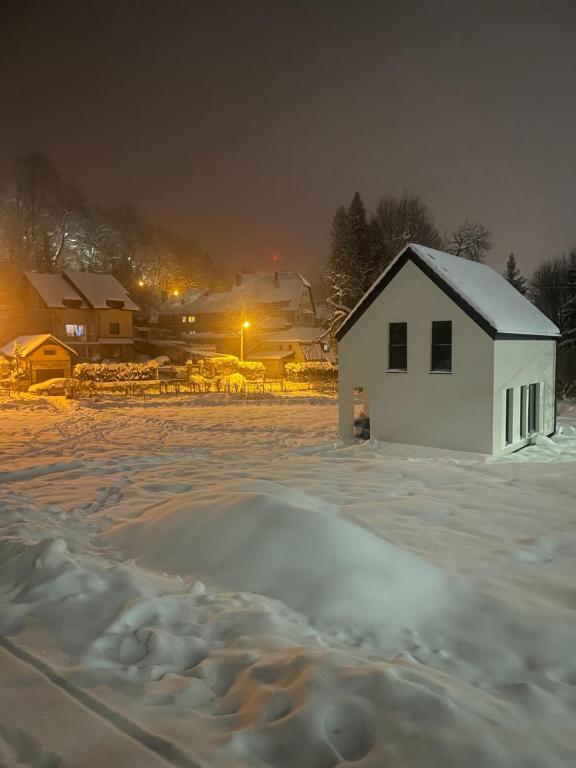 a white house in a snowy field at night at MINIMAL. Dom całoroczny w górach in Duszniki Zdrój
