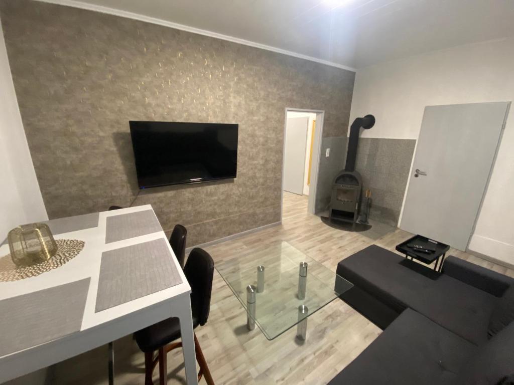 a living room with a table and a tv on a wall at Gemütliches Apartment mit Kamin in Oldenburg