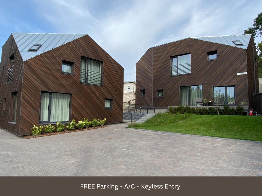 2 casas grandes de madera con ventanas en la entrada en Green Hill Apartments, en Kaunas