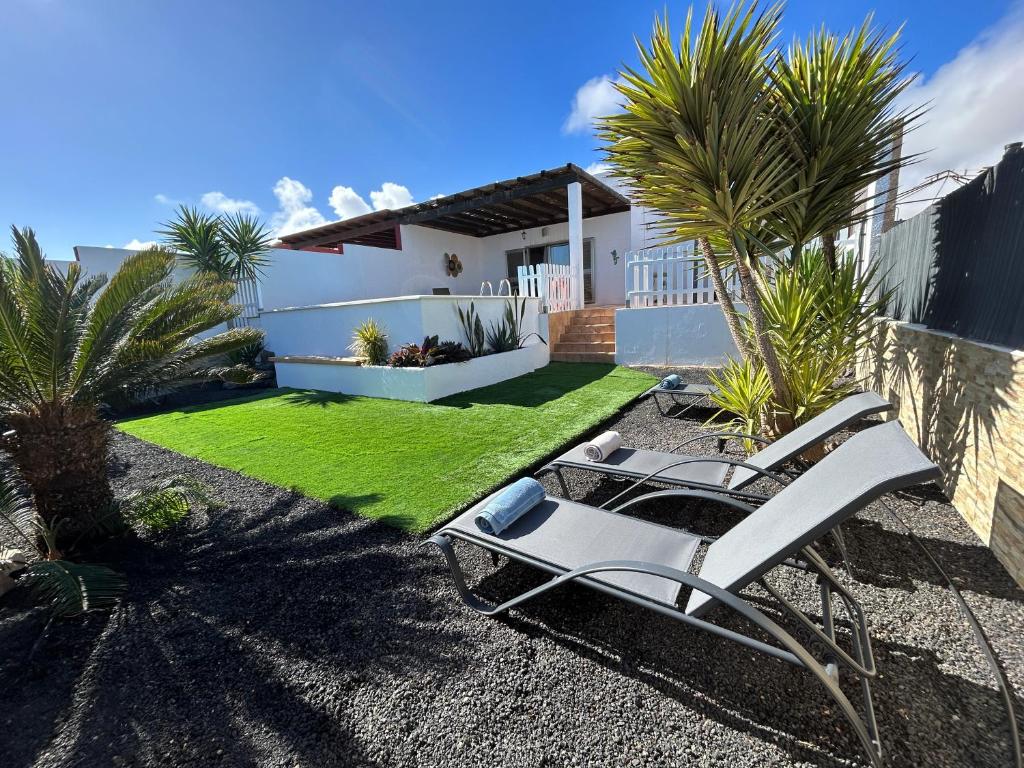 een tuin met 2 ligstoelen en palmbomen bij Villa Dinateli, Salinas Golf in Caleta De Fuste