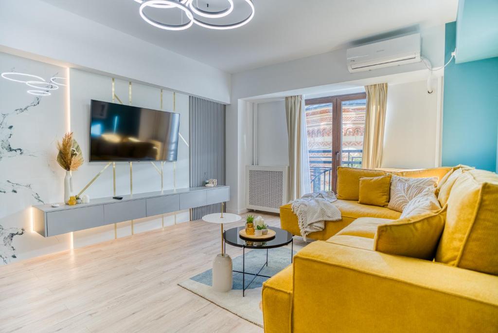 a living room with a yellow couch and a tv at Hi-lux Ultracentral - 4BR Superior - Amazing View in Bucharest