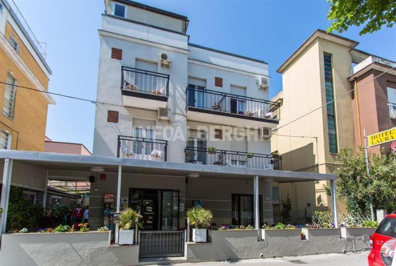 a white building with balconies on the side of it at Hotel Laura Beach in Rimini