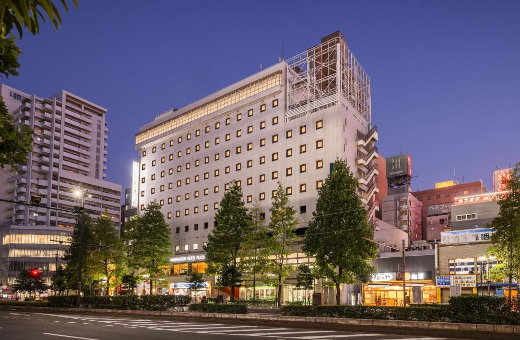 Okayama Washington Hotel Plaza في أوكاياما: مبنى ابيض كبير على شارع المدينة بالليل