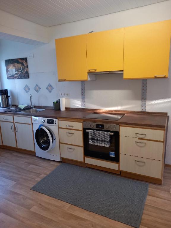 eine Küche mit gelben Schränken und einer Waschmaschine in der Unterkunft Schöne Ferienwohnung in Gernsbach in Gernsbach