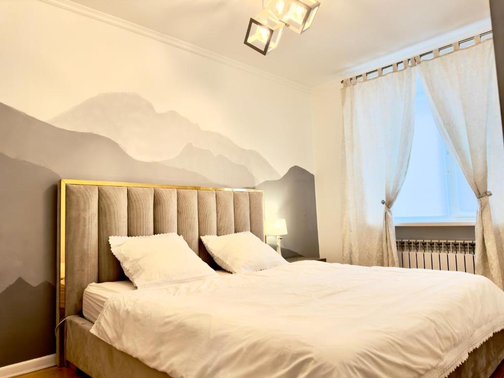 - une chambre avec un grand lit orné d'une fresque murale représentant la montagne dans l'établissement Двушка около Академии Scandinavian Style, à Atyraū