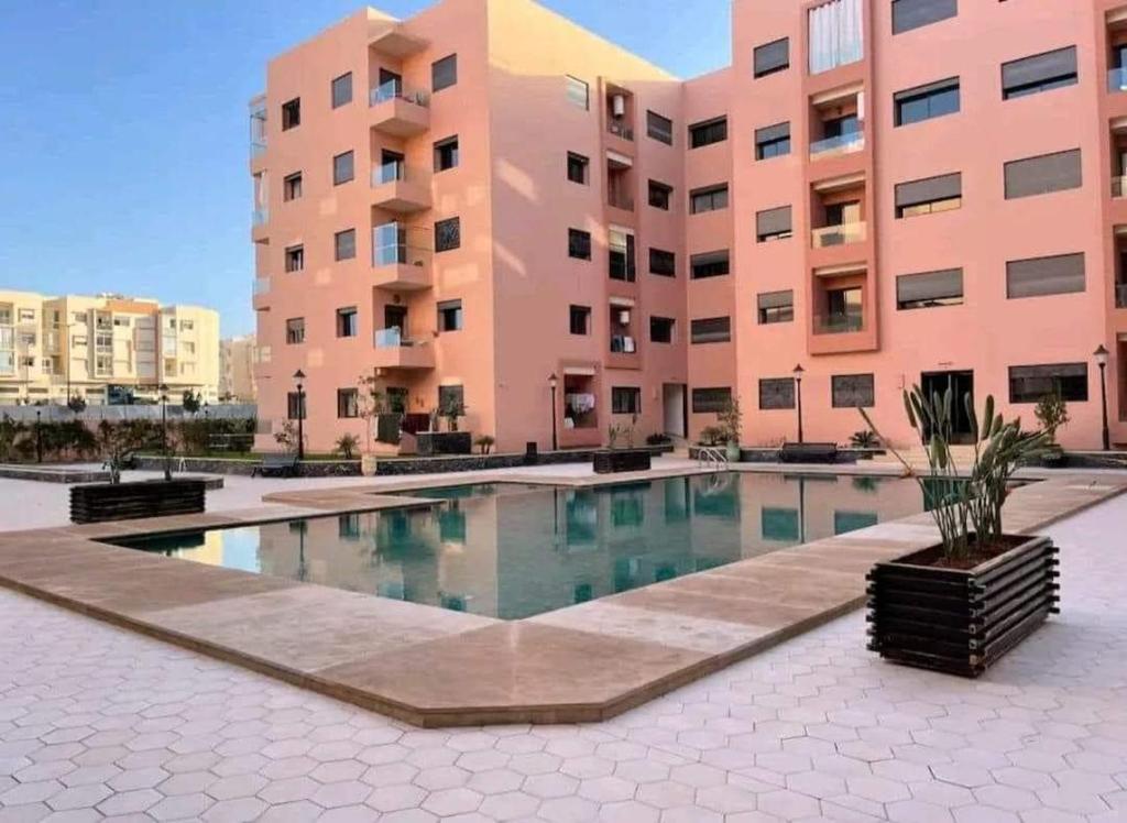 einen Innenhof mit einem Pool vor einem Gebäude in der Unterkunft Appartement Cosy Residence avec 2 Piscines in Marrakesch