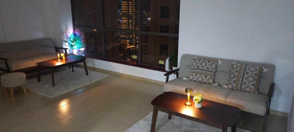 a living room with a couch and tables and a window at JBR Beach Synergy Inn in Dubai