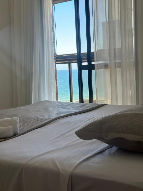 Cama con ventana con vistas al océano en Surpreenda-se excelente apartamento com vista mar, en Salvador