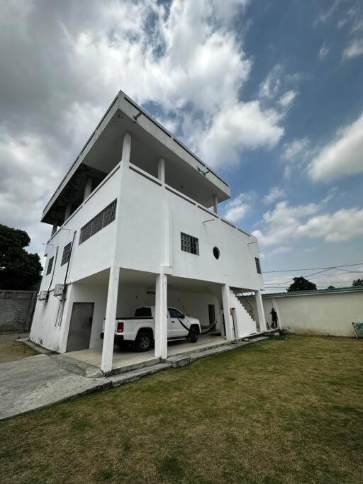 una casa bianca con una macchina parcheggiata di fronte di Depa de 3 dormitorios y parqueo a Guayaquil