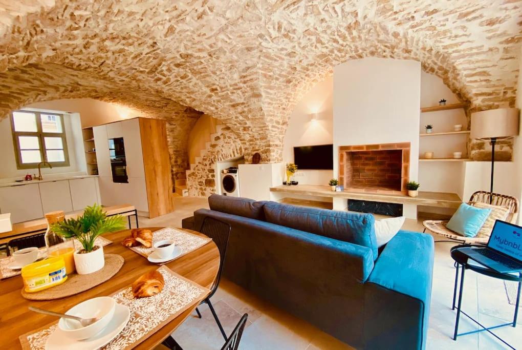 een woonkamer met een blauwe bank en een tafel bij Terra Nostra - Townhouse - Swimming pool in Nîmes