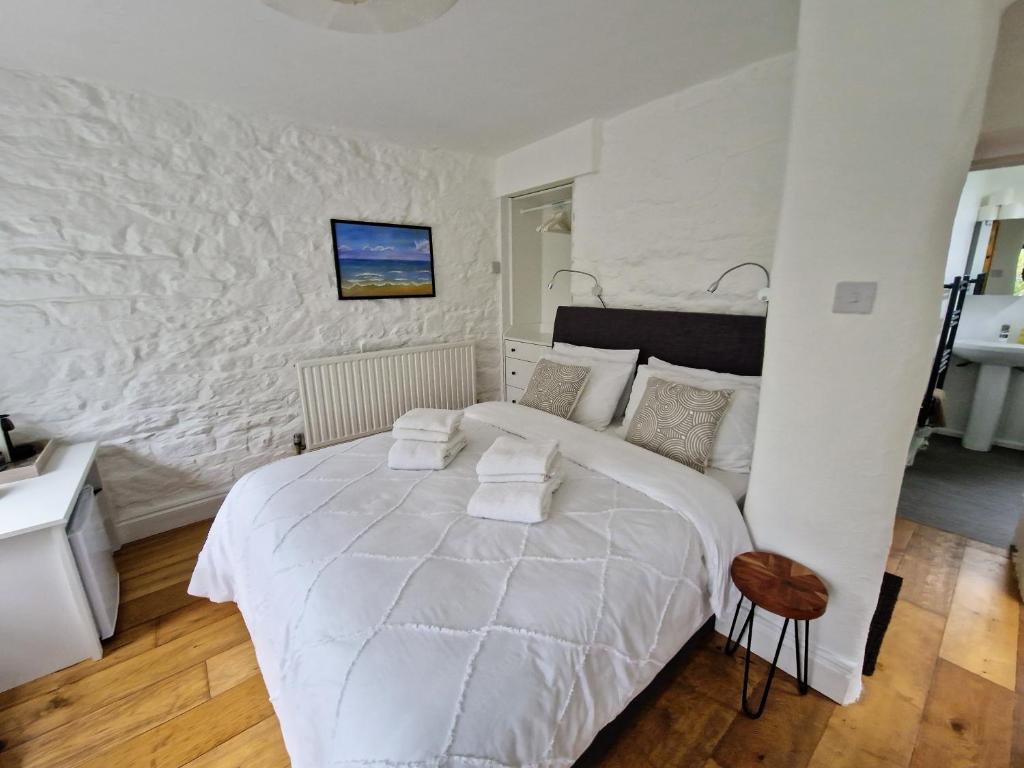a white bedroom with a large bed and a wall at Primrose Cottage in Helston
