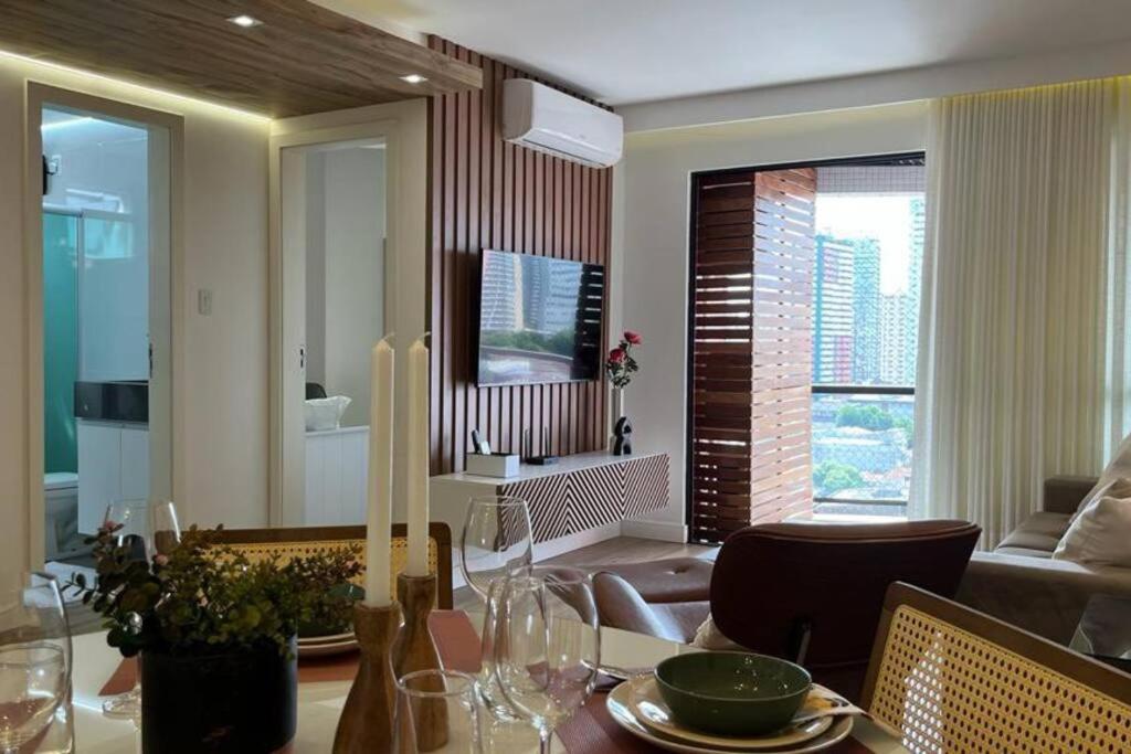 a dining room with a table and a living room at Espaçoso, moderno e excelente localização in Belém