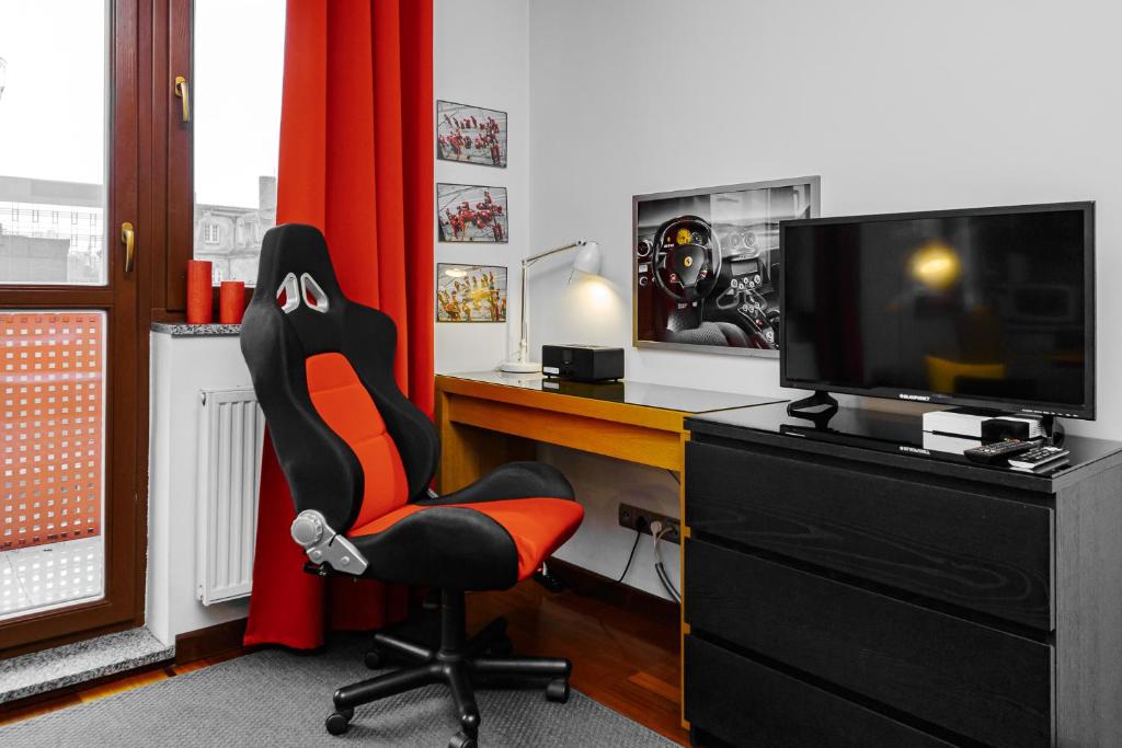 una oficina con escritorio con silla y TV en Aura Apartment, en Wroclaw