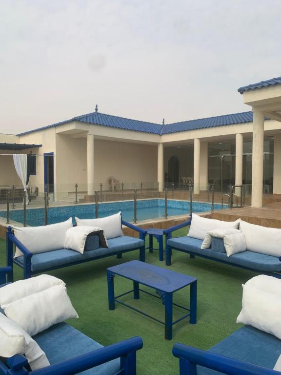 un grupo de sofás azules sentados junto a una piscina en شاليه لمه, en Dammam