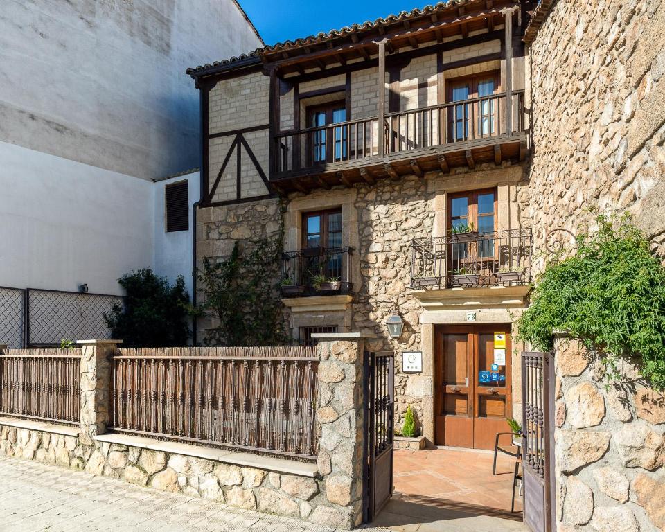 a stone house with a wooden fence in front of it at Casa Rural La Fuente del Jerte in Navaconcejo