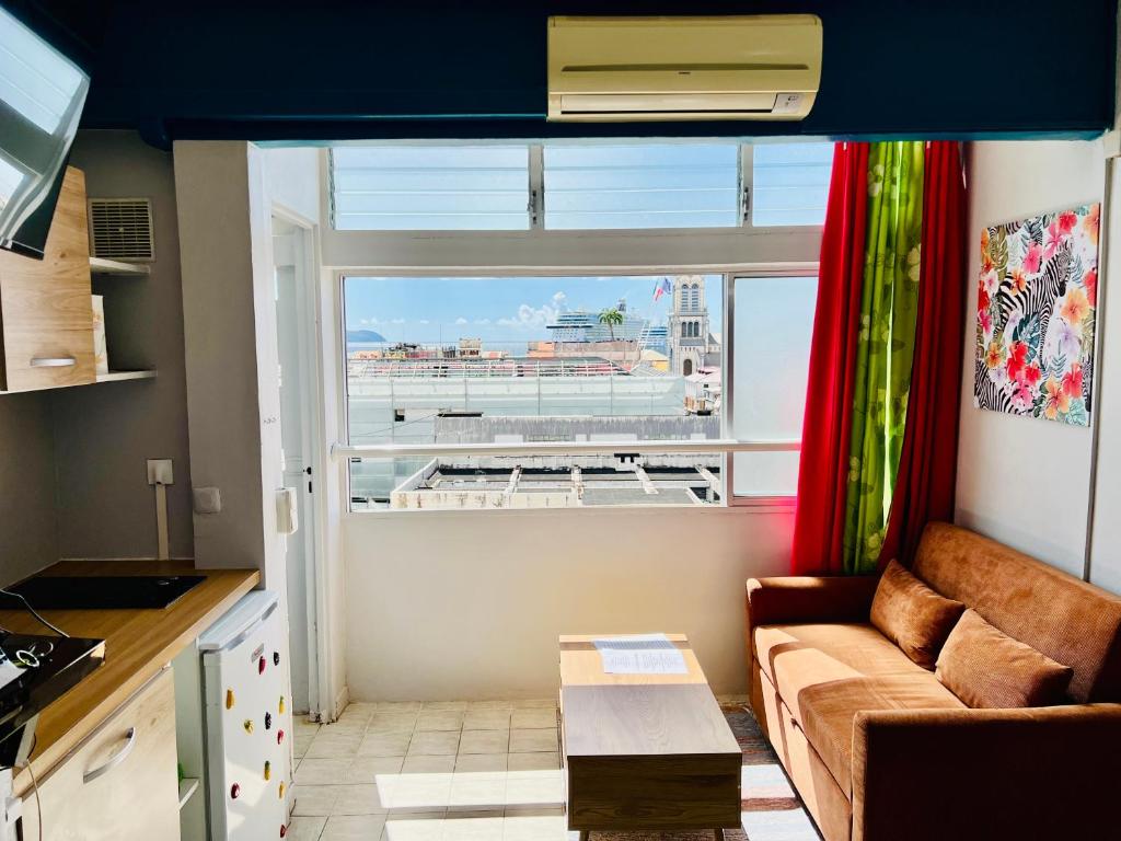 a living room with a couch and a large window at Belle vue in Fort-de-France